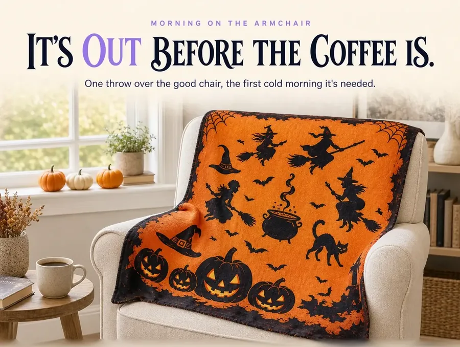 The witch-print throw draped over an armchair in a sunlit living room, small pumpkins on the windowsill.