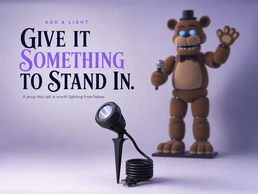 A single black stake spotlight on a pale ground with the bear out of focus behind it.
