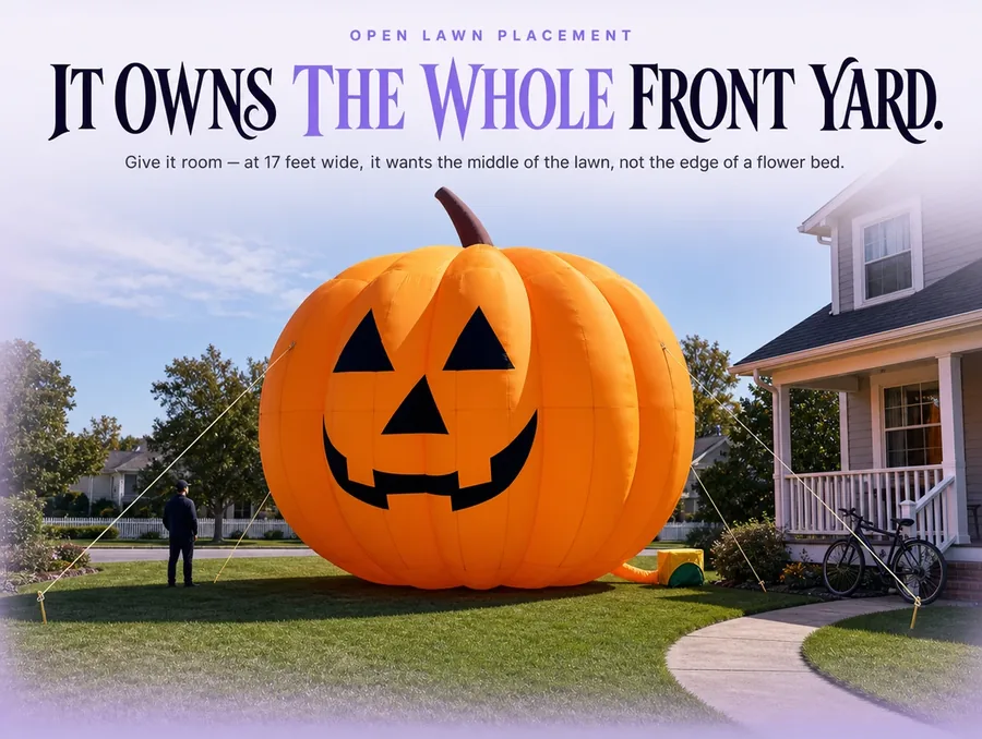 The giant inflatable pumpkin set on an open front lawn in daylight beside a garden path.