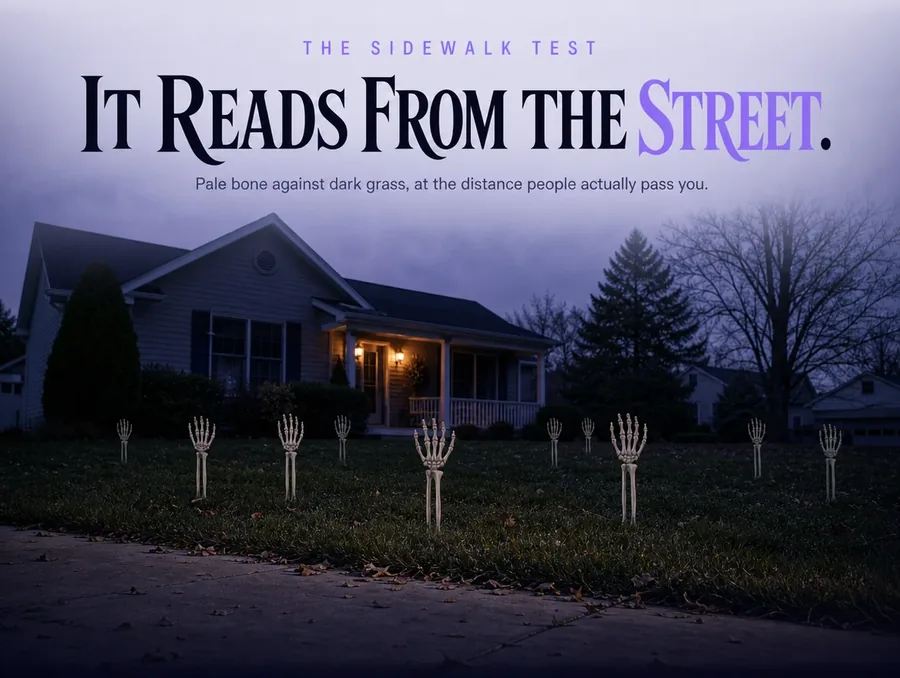 The planted arms seen small from the public sidewalk, pale shapes scattered across a dark lawn.