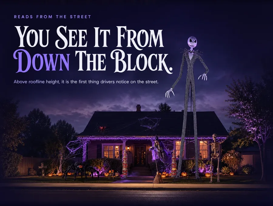 Wide view from across the street: the tall figure visible above the roofline of a decorated house.