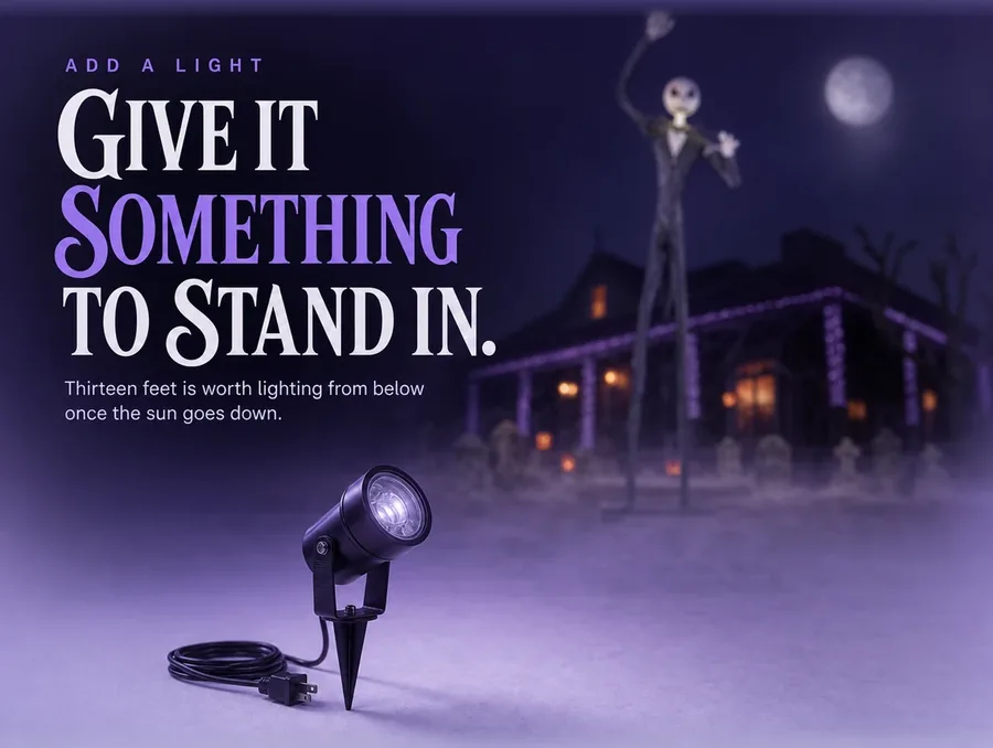A single black stake spotlight on a pale ground with the tall figure out of focus behind.