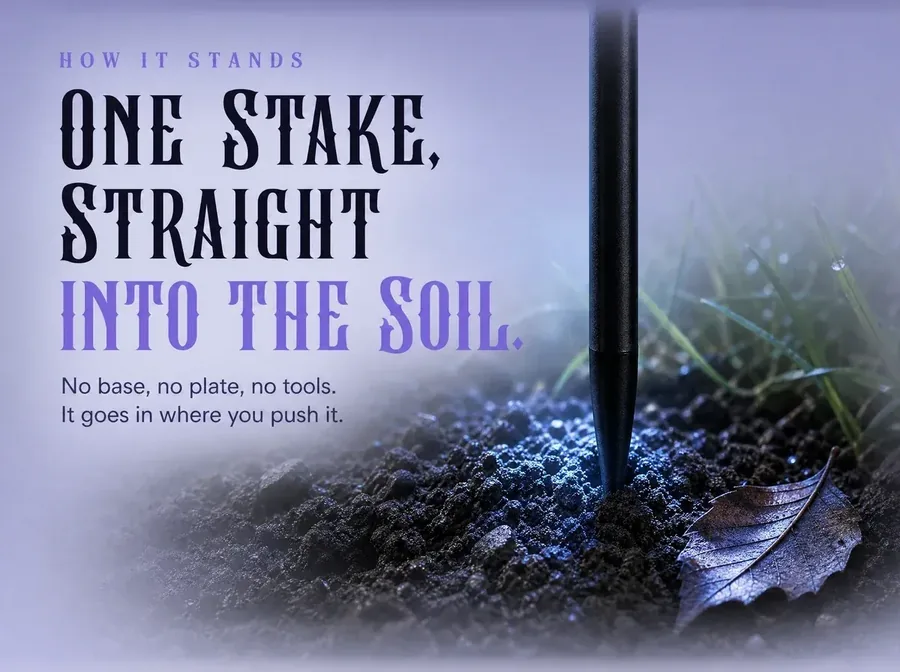 Ground-level view of the thin metal stake pushed straight into dark garden soil