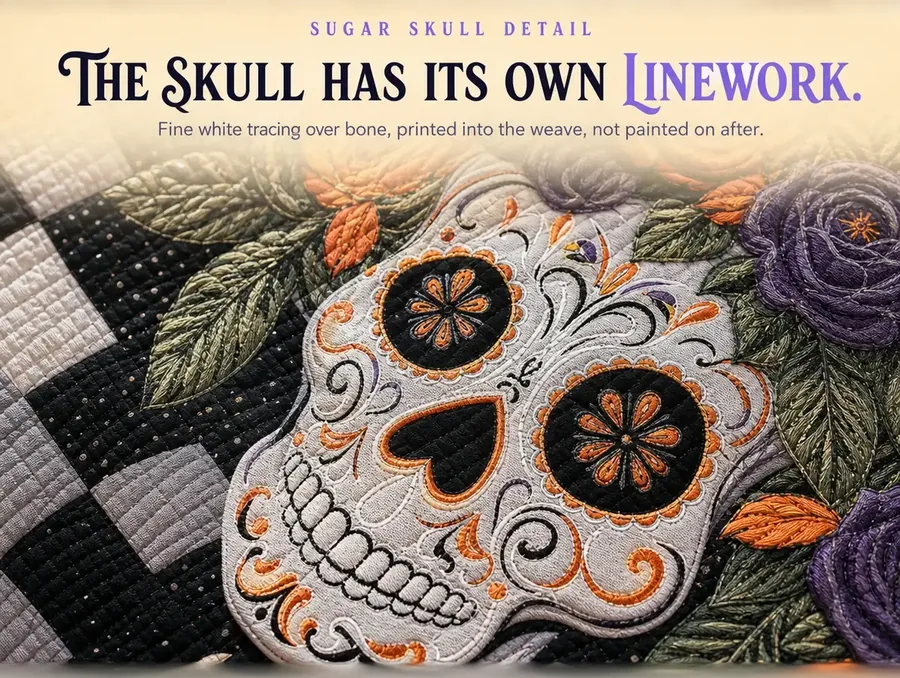 Macro crop of the sugar skull's painted linework and orange-ringed eye socket on the quilted fabric.