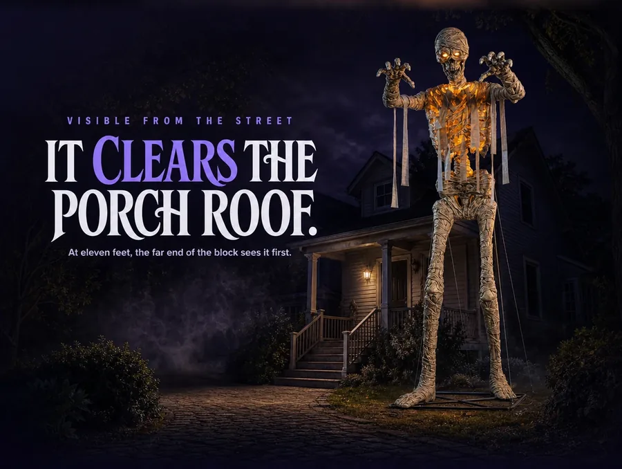 Wide night shot of the glowing mummy standing beside a dark house, clearing the porch roofline.